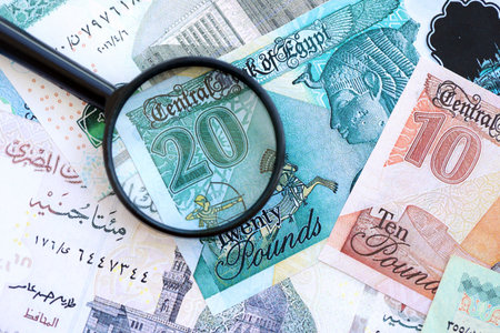 Egyptian pound currency money bills and magnifying glass close up. The concept of financial...