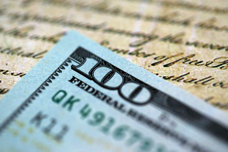 One hundred US dollar bills and United States Constitution page fragment. Concept of lawsuit and...