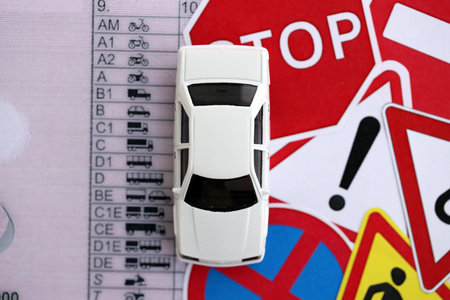 Driving school concept. Toy car and road signs on driver license close up