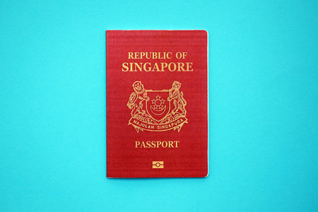 Singapore passport book on light blue paper background close up. Travel document on blue surface