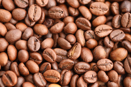 Big pile of fresh roasted brown coffee beans as flat background photo image with visible details...