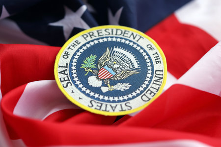 KYIV, UKRAINE - DECEMBER 13, 2025 Seal of the President of the United States sticker on United States of America folded waving flag with stars and stripes close upのeditorial素材
