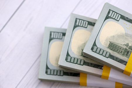 Three packs of ten thousand US dollar bills on wooden background. Packs of hundred dollar bills in...