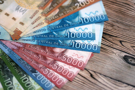 Big amount of chilean pesos money bills banknotes on wooden table. Huge quantity of paper money from...