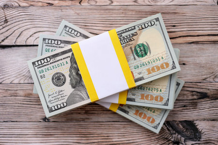 Three packs of ten thousand US dollar bills on wooden background. Packs of hundred dollar bills in...