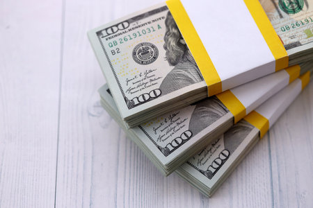 Three packs of ten thousand US dollar bills on wooden background. Packs of hundred dollar bills in...