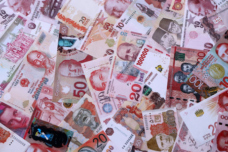 Various currencies money bills banknotes in red color. Many cash bills from different countries in big pile close up. World economy and currency exchange conceptの写真素材