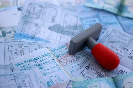 Border crossing stamp on big amount of passport pages full of colorful stamps after travel and...