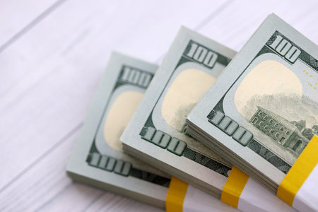 Three packs of ten thousand US dollar bills on wooden background. Packs of hundred dollar bills in stack on white wood planks close upの写真素材