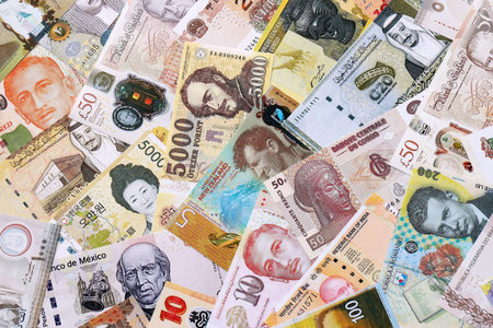 Various currencies money bills banknotes in yellow and orange color. Many cash bills from different countries in big pile close up. World economy and currency exchange conceptの写真素材