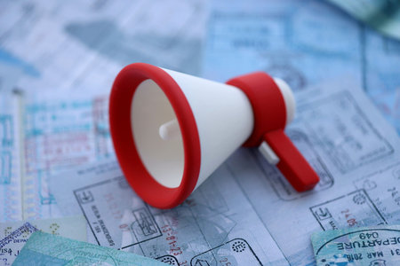 Megaphone on passport pages full of colorful stamp prints after travel and tourism. touristic announcements and offers concept. Travel around the worldの写真素材