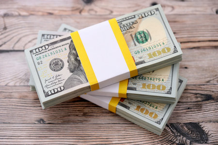 Three packs of ten thousand US dollar bills on wooden background. Packs of hundred dollar bills in...