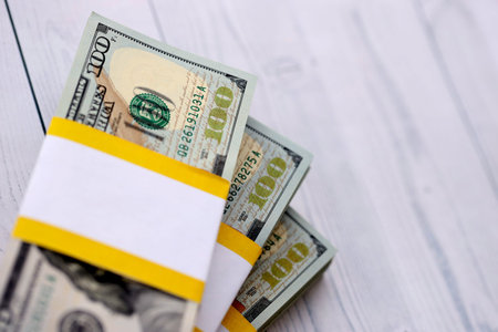 Three packs of ten thousand US dollar bills on wooden background. Packs of hundred dollar bills in...