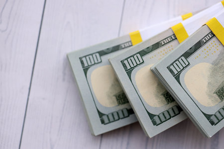 Three packs of ten thousand US dollar bills on wooden background. Packs of hundred dollar bills in...