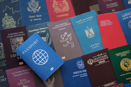 Fictional passport book travel document on big amount of real passport covers of various different...