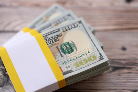 Three packs of ten thousand US dollar bills on wooden background. Packs of hundred dollar bills in stack on brown wood planks close upの写真素材