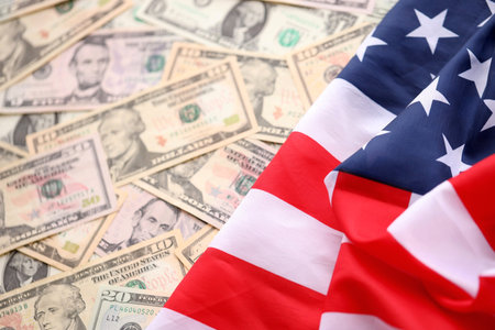American Flag Draped Over Piles of US Dollar Bills. Symbolizing Wealth and Patriotism in the USA....