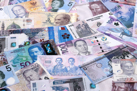 Big amount of various currencies money bills banknotes in full frame. Many cash bills from different countries in big pile close up. World economy and currency exchange conceptの写真素材