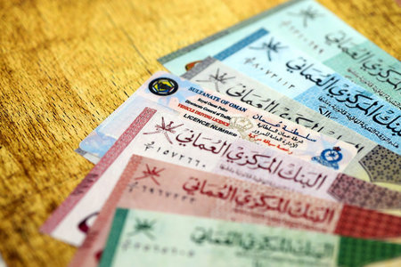 Oman driving license among Oman rial money bills on table close up. Drivers permit with Oman...