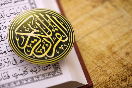 Sign with Al Quran inscription on Muslim holy book in mosque. Details of arabic calligraphy on...