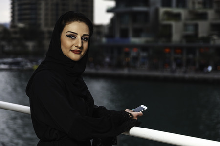 Young and beautiful Emirati woman standing by the canal in Dubai Marina.