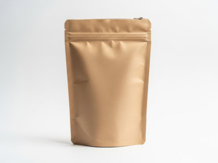 The image shows a single, upright, brown-colored stand-up pouch with a zipper closure at the top. The pouch appears to be made of a shiny, metallic material, likely aluminum foil, which is commonly used for packaging food items such as coffee, tea, or snacks. The pouch is set against a plain white background, making it the sole focus of the image. The zipper is partially open, revealing a small gap at the top.の素材