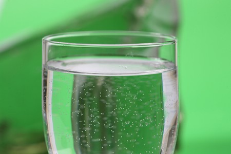 Glass of water and ice on a green background の写真素材