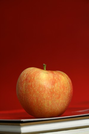 red apple resting on the book with chalk board as background の写真素材