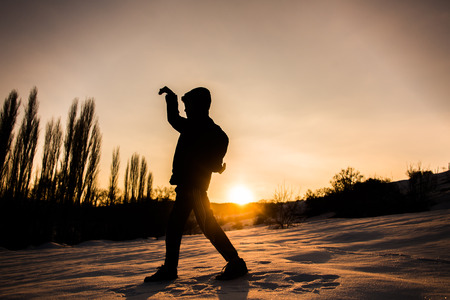 The silhouette of a young boy at sunset in winterの写真素材