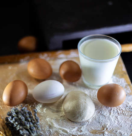 A glass of milk and a set of eggs on a wooden board