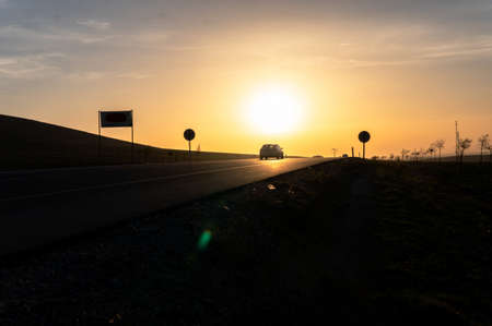 Sunset on the road in the countryside. The sun goes down over the horizon.の写真素材