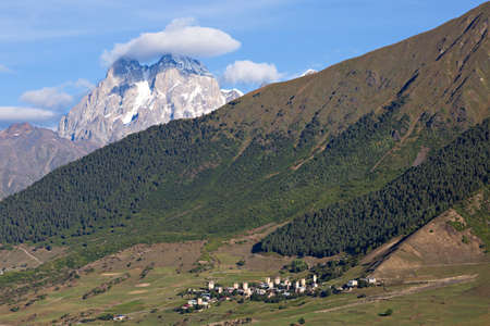 Mount Ushba, one of the peaks of the Caucasus Mountains and village houses in Georgia