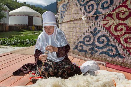 Kazakh elderly lady in local nomadic dress spinning the wool.のeditorial素材