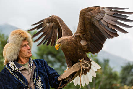 Kazakh eagle hunter in traditional costumes holding his golden eagle in Almaty, Kazakhstan.