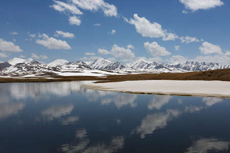 Mountain lake on top of the mountains in Barskaun, with reflections in water in Kyrgyzstan