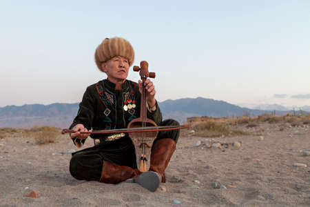 Kyrgyz musician playing traditional musical instrument known as Komuz, in Issyk Kul, Kyrgyzstanのeditorial素材