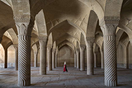 Vakil Mosque with an Iranian woman in red dress under its arches, in Shiraz, Iranのeditorial素材