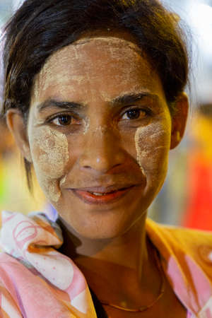 Portrait of local woman with thanaka on her face, in Yangon, Myanmar. Thanaka is cosmetic paste made from ground barkのeditorial素材