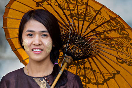 Local girl with thanaka on her face, in Mandalay, Myanmar. Thanaka is cosmetic paste made from...