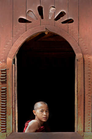 Young monk looking out the window of the monastery, in Inle Lake, Myanmarのeditorial素材