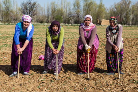 Women working in the field rest leaning on their hoe near Konya, Turkey.のeditorial素材