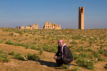 Local man wearing traditional headdress with the ruins of ancient city of Harran in the background, Sanliurfa, Turkey.のeditorial素材
