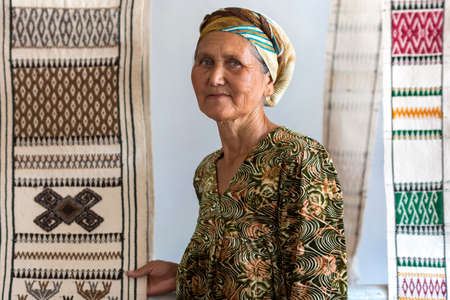 Local woman holding the rugs she makes in Nukus, Uzbekistan