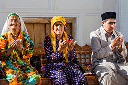 Uzbek women and man praying in the historical cemetery of Shahi Zinda, in Samarkand, Uzbekistan.のeditorial素材