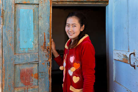 Central asian girl looking through wooden doors, in Nukus, Uzbekistanのeditorial素材