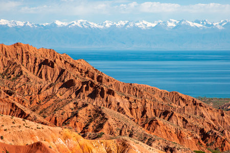 Red rock formations with Issyk Kul Lake in the background in Kaji Say, Kyrgyzstan,の写真素材