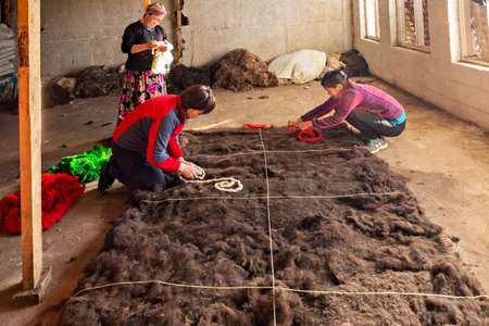 Kyrgyz women making felt carpet in traditional way, in Issyk Kul, Kyrgyzstan.のeditorial素材