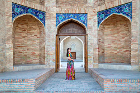 Uzbek woman in local dress with the Barak Khan Madrasa in the backgroundのeditorial素材