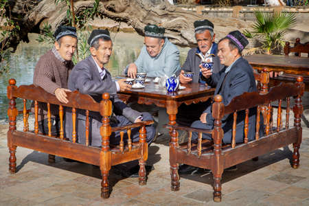 Group of Uzbek men wearing traditional hats drink tea in Bukhara, Uzbekistanのeditorial素材