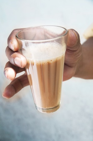 Close-up of man's hand holding glass of chaiの写真素材
